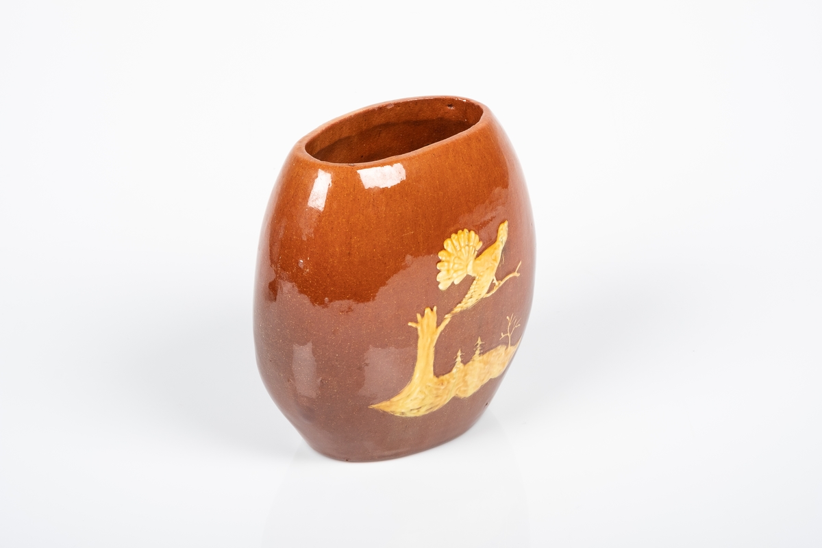 På baksiden av vasen er det motiv av en tiurleik stående på en kvist fra en trestamme. I bakgrunnen ser man to grantrær og et annet tre uten blader.
