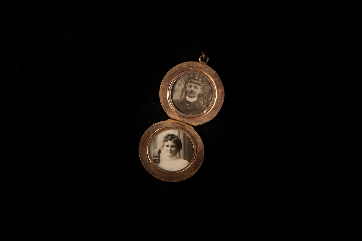 En rund medaljong i förgylld mässing. På framsidan finns ett graverat mönster och en infattad vit pärla. Inne medaljongen finns två fotografiier. Baksidan är sliten och där har den ärgat.