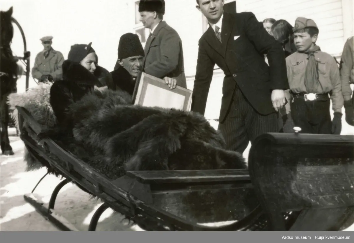 Folk som i slede medbragt gave og speidergutt stående ved siden av. Under Kronprinsparets besøk i Vadsø i 1934.