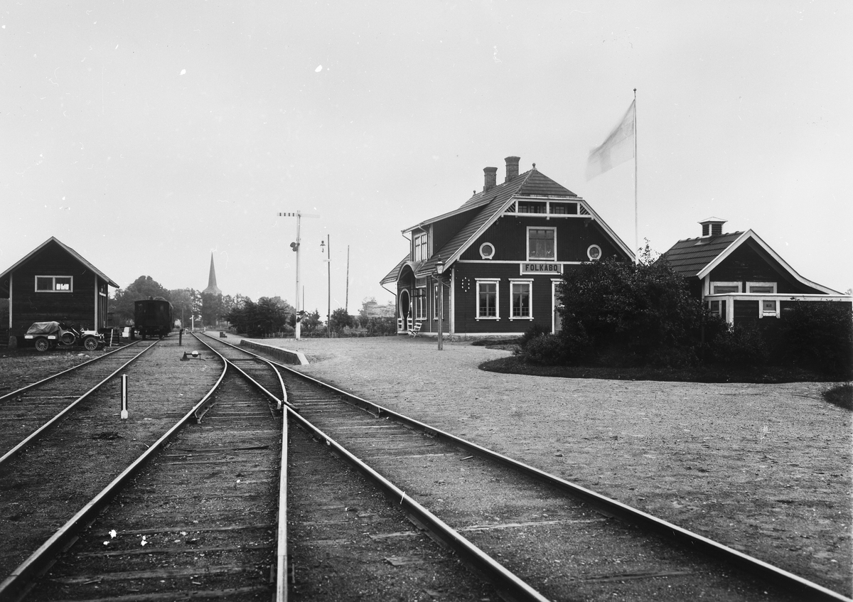 Järnvägsstationen i Folkabo anlagd av Tidaholms järnväg 1906. Notera att flaggan ser inverterad ut, detta är en bieffekt av den typ av film, ortokromatisk film, som användes vid den här tiden.