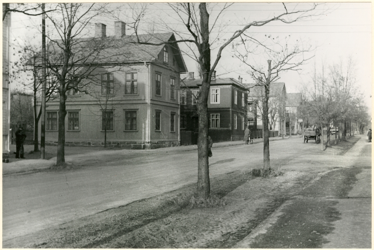 Längs gata med trafikanter står hus på rad. - Järnvägsmuseet ...