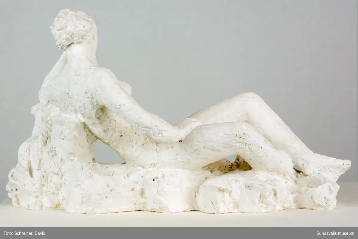 En skulptur i form av en liggande kvinna med huvudet vilande i ena handen.