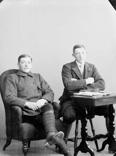 Bröderna Carlsson. Två sittande unga män, Elfin till vänster i en fåtölj och Gunnar på en stol med armarna lutade på ett bord.