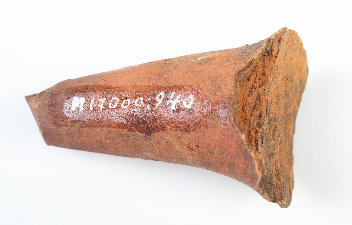 Koniskt ben, sannolikt från en trebensgryta i yngre rödgods. Brun glasyr på kärlbukens insida. Tillverkad i södra Skandinavien.