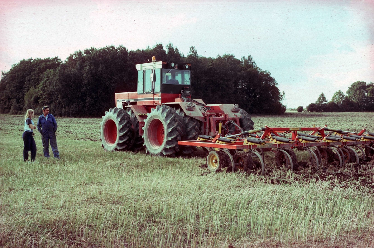 Okänd kvinna och traktorförare Stig Ahlin vid traktor med harv, Hacksta gård, Enköpings-Näs socken, Uppland 1981 - 1982