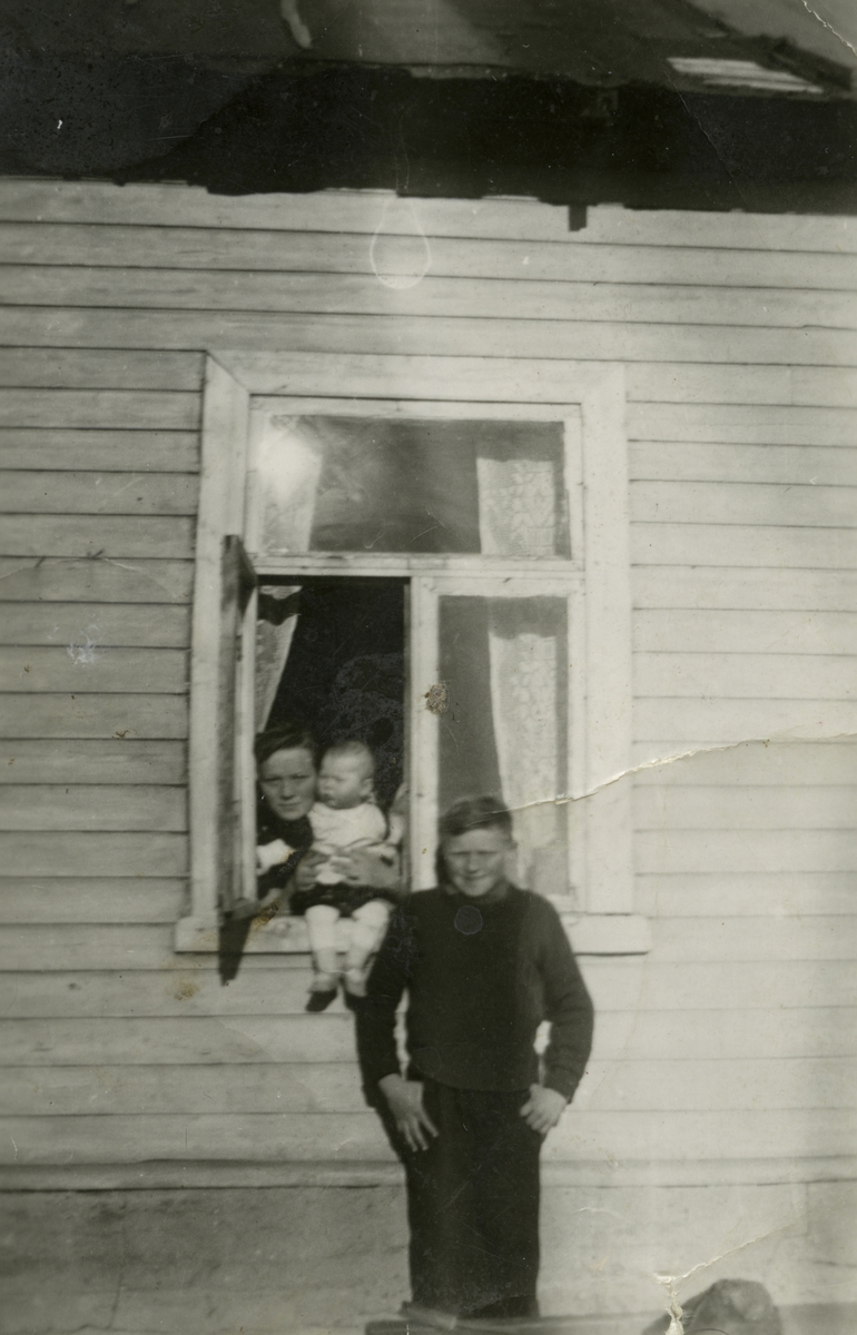 Magnhild Ittelin med sin niese Annelise (Ann Elisabeth). Foran vinduet står Wilhelm Ittelin, Vestre Jakobselv.