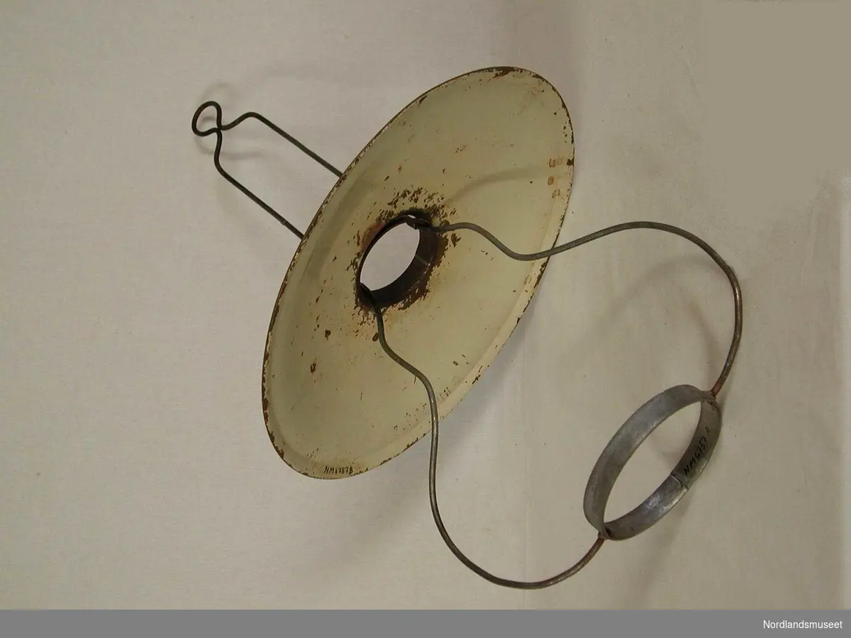 Form: Tradisjonell og billig form. En metallbøyle m/ring nede til å sette lampen i og en oppe til å henge skjermen på.En liten bøyle øverst for oppheng. Behandlet med dip,jan. 1990.
