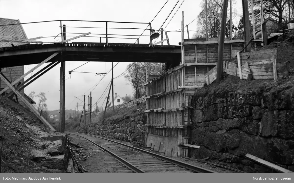 Arbeid med heving av overgangsbro i forbindelse med elektrifiseringen av Vossebanen. Forskaling av landkar. Her ved Jansen fabrikker ved Midttun, sett i retning Bergen.
