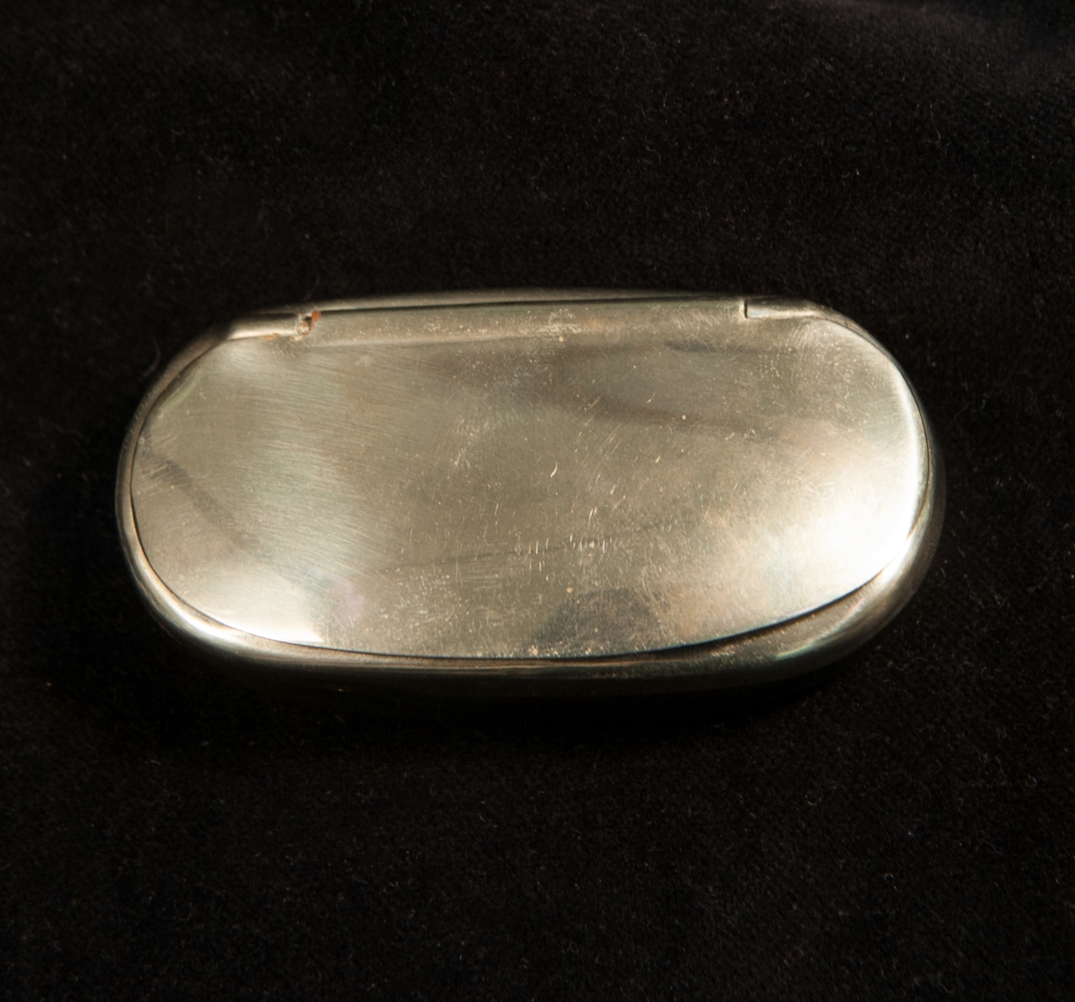 En oval snusdosa av gråvitt kohorn med lock m.m. i nysilver.