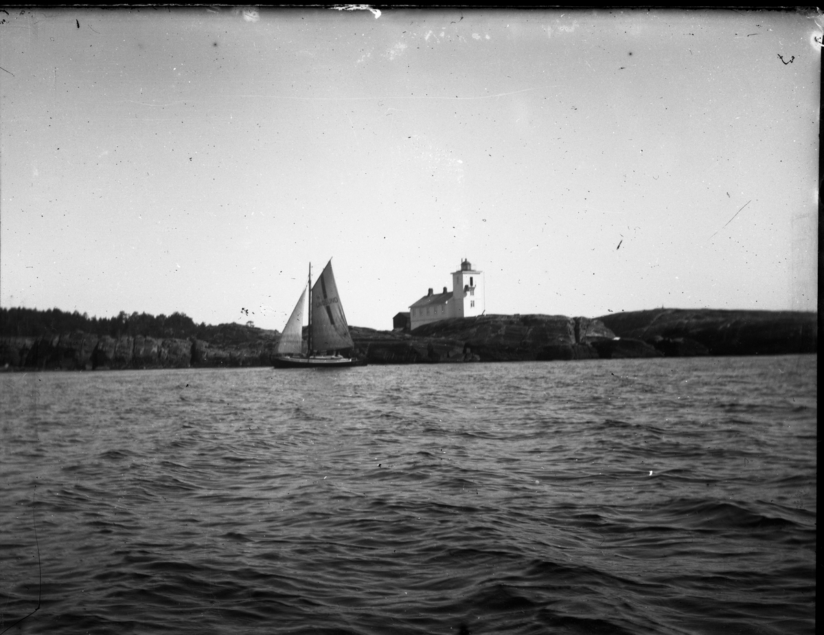 Losskøyta Langesund for fulle seil forbi Langøytangen fyr. Fotografiet er tatt ant. før 1913 da fyret ble forandret. Samtidig ble maskinhus til tåkelur bygget.

På seilet står det: 4 LNGSUND

Antatt fotosamling etter Anders Johnsen.