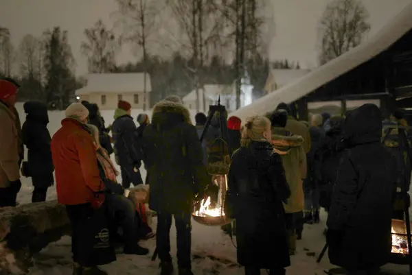 Folk på omvisning i snøen i kveldsmørket i låven