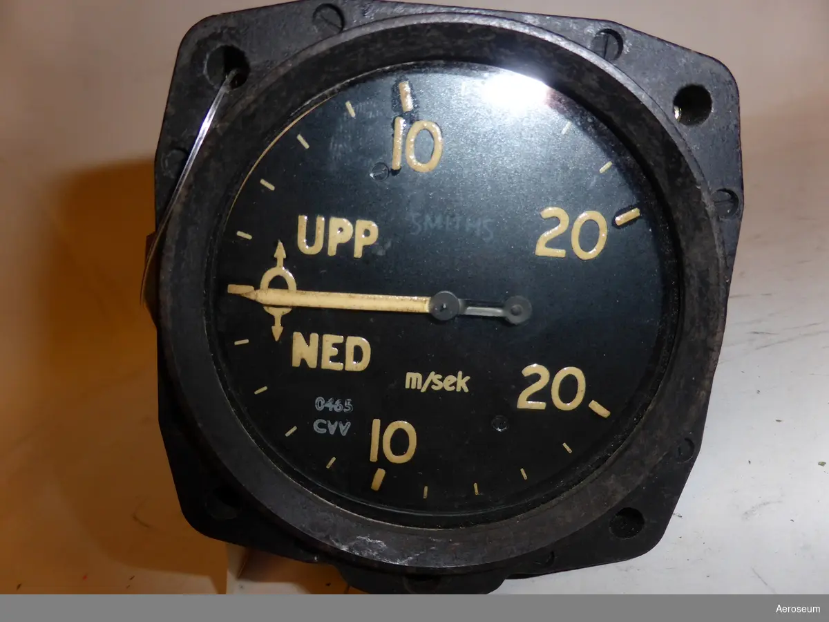 En stig- och sjunkhastighetsmätare (eller som det kallas på svenska, en variometer) graderad  i meter per sekund (M/Sek).

Den är svart och gjord i metall.

I displayen står det: "0465 CVV", "UPP NED m/sek" och "SMITHS". På en ettikett fastklistrad på sidan går det att läsa: "9250 2.00". På botten av instrumentet står det: "SS & S LTD LONDON", och "RATE OF CLIMB INDICATOR 21RC/PC/M/SE BRIT. PAT. NO 507993 S.S. & S. LTD MADE IN ENGLAND CODE [tom ruta] SER NO 4896/18"