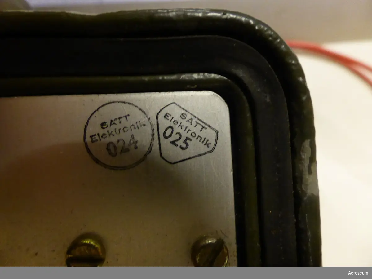 En Tonsvarare i en grön metallåda. I lådan är föremålet silvrigt med två svarta och två röda rattar/knappar. Tillverkad av SATT Elektronik. På lådan finns det en klistrad lapp där det står: "Solrosen" i röd penna. På lådan står det också: "SATT Elektronik STOCKHOLM - SWEDEN". I öppnings- och låsningsmekanismen står det: "NIELSEN HDWE HARTDORD". Inne i locket står det "V549632", "BET M3743-605000 BEN TONSVARARE URSPR- BET SATT 3-5948999 IND- NR 2042", och under detta sitter en lite skylt i locket med instruktion om hur tonsvararen ska användas. På själva mekanismen som sitter fast i lådan står det: "L",  "A", "SATT Elektronik 024", "SATT Elektronik 025", och "BET F6064-000747 BEN TONSVARARINSATS URSPR- BET SATT 52511".