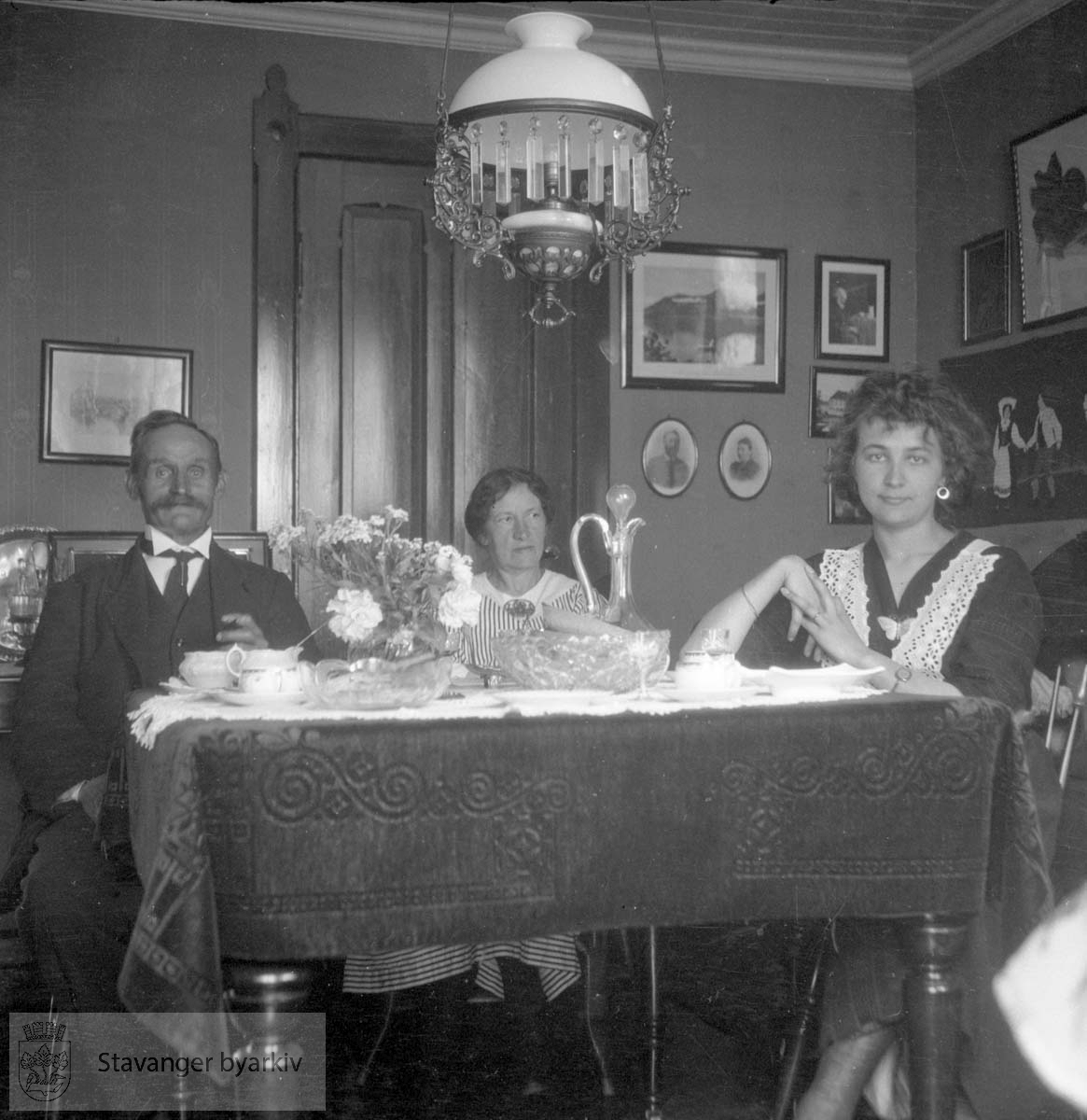 Mann og to kvinner ved spisebord