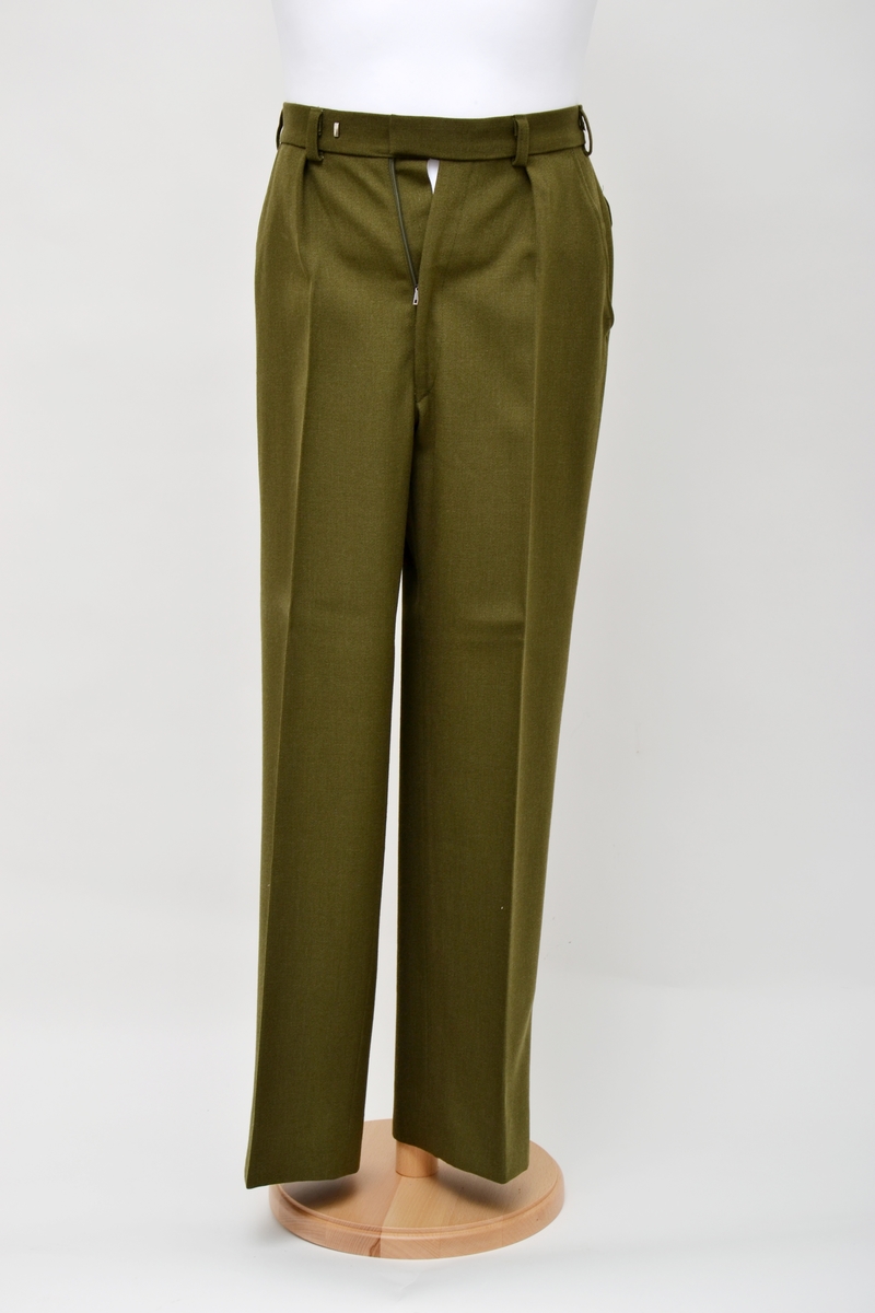 Militærgrønn bukse i ullstoff med to stikklommer i front og to baklommer med klaff. Lukkes med glidelås og dobbelhemper.