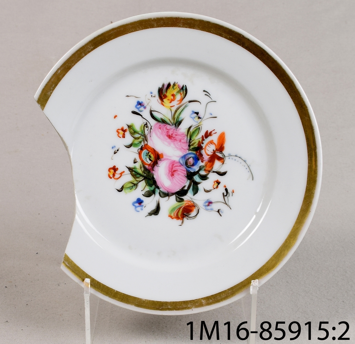 Rund tallrik av vitt porslin med handmålad blomdekor i många färger i mitten samt slät kant med handmålad guldrand.