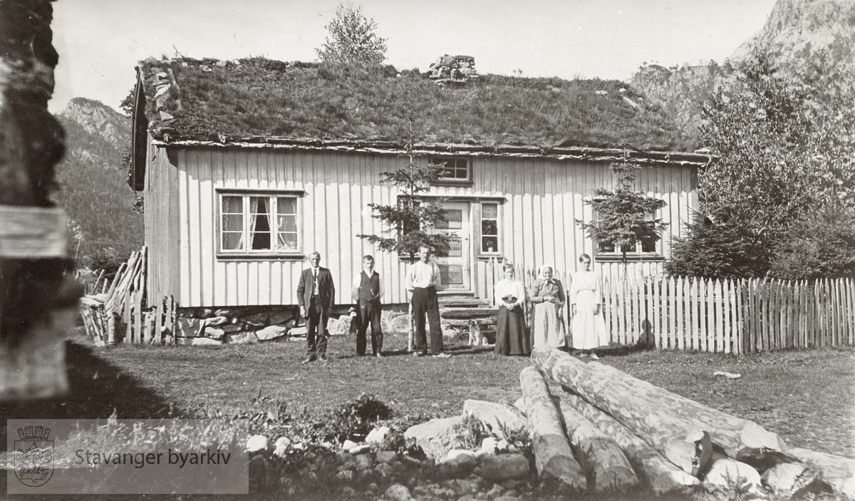 Tre menn og tre kvinner foran hus i Rusdal