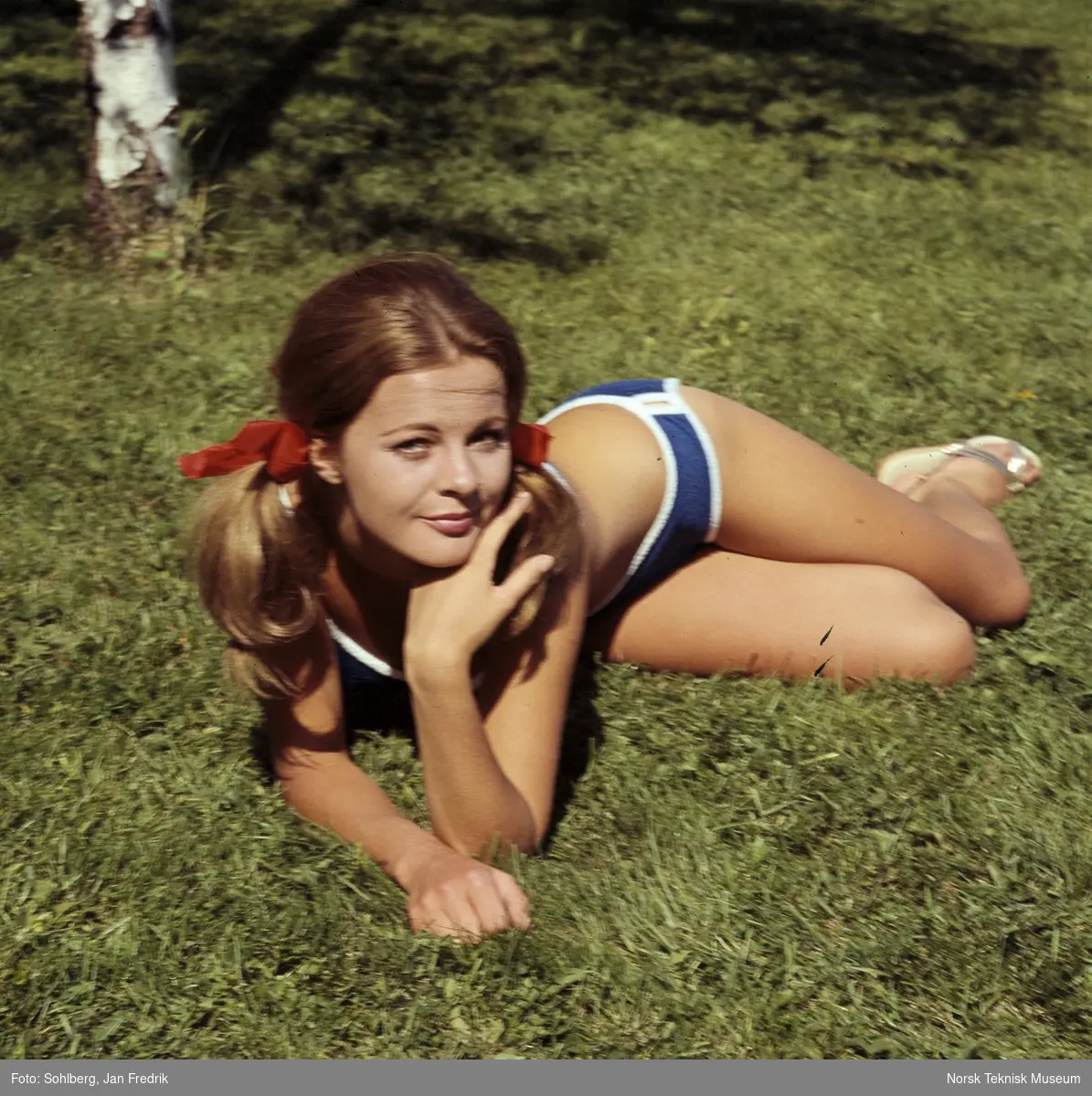 Kvinnelig modell viser bademote. Hun er fotografert liggende i gresset.