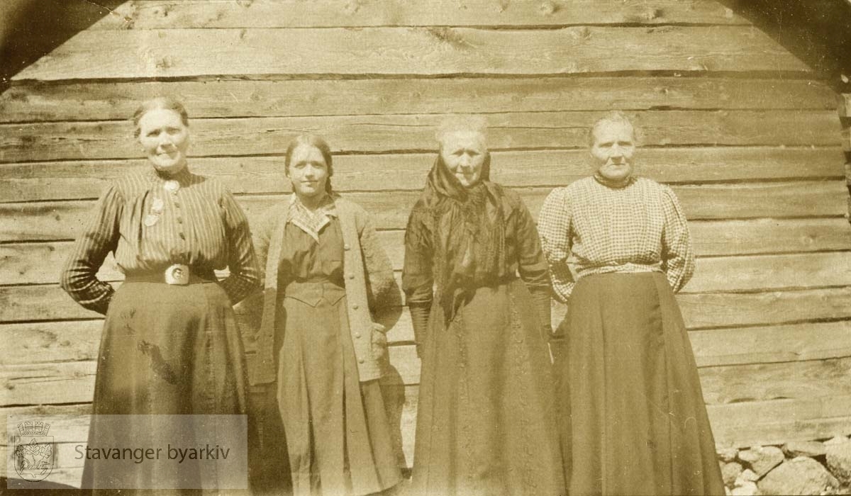 Fire kvinner oppstilt langs vegg.