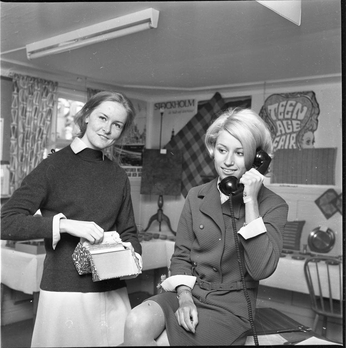 Turistvärdinnan Kerstin Oddbjörn bläddrar bland katalogkort och föreståndaren Kerstin Carlsson i telefon. De är båda personal på turistbyrån i Gränna 1968.