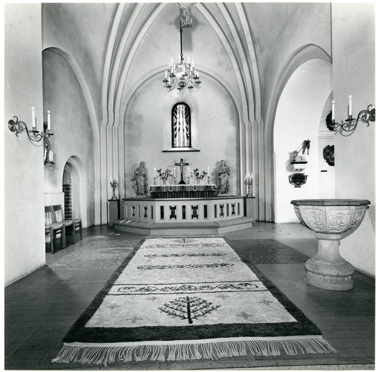 Badelunda sn, kyrkan.
Interiör med altaret, dopfunt, matta m.m., 1983.