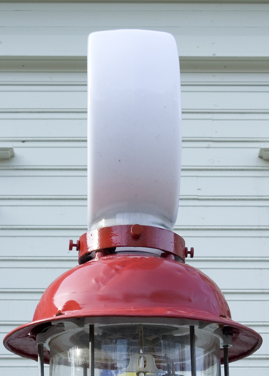 Pumpglob, fabriksgjord, av vitt glas. Modell där en "kort" cylinder sitter på ett ihåligt fäste. Inuti finns en montering för elektriskt ljus. På båda sidorna sitter logotypen: en rund ram i rött, korsad av STANDARD OIL i blått med rött streck över och under.