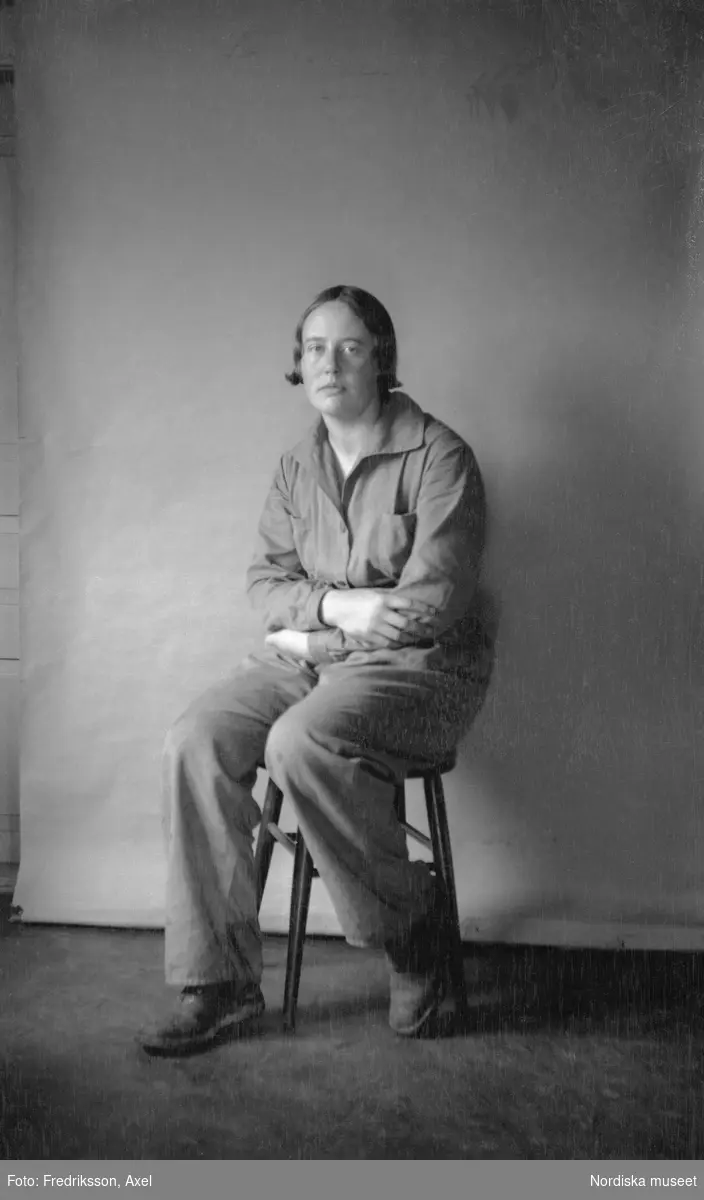 Edit Rank, Granvik , Finland, sittande i helfigur på en pall iklädd arbetskläder. Elev vid Fogelstad ladugården 1932-33