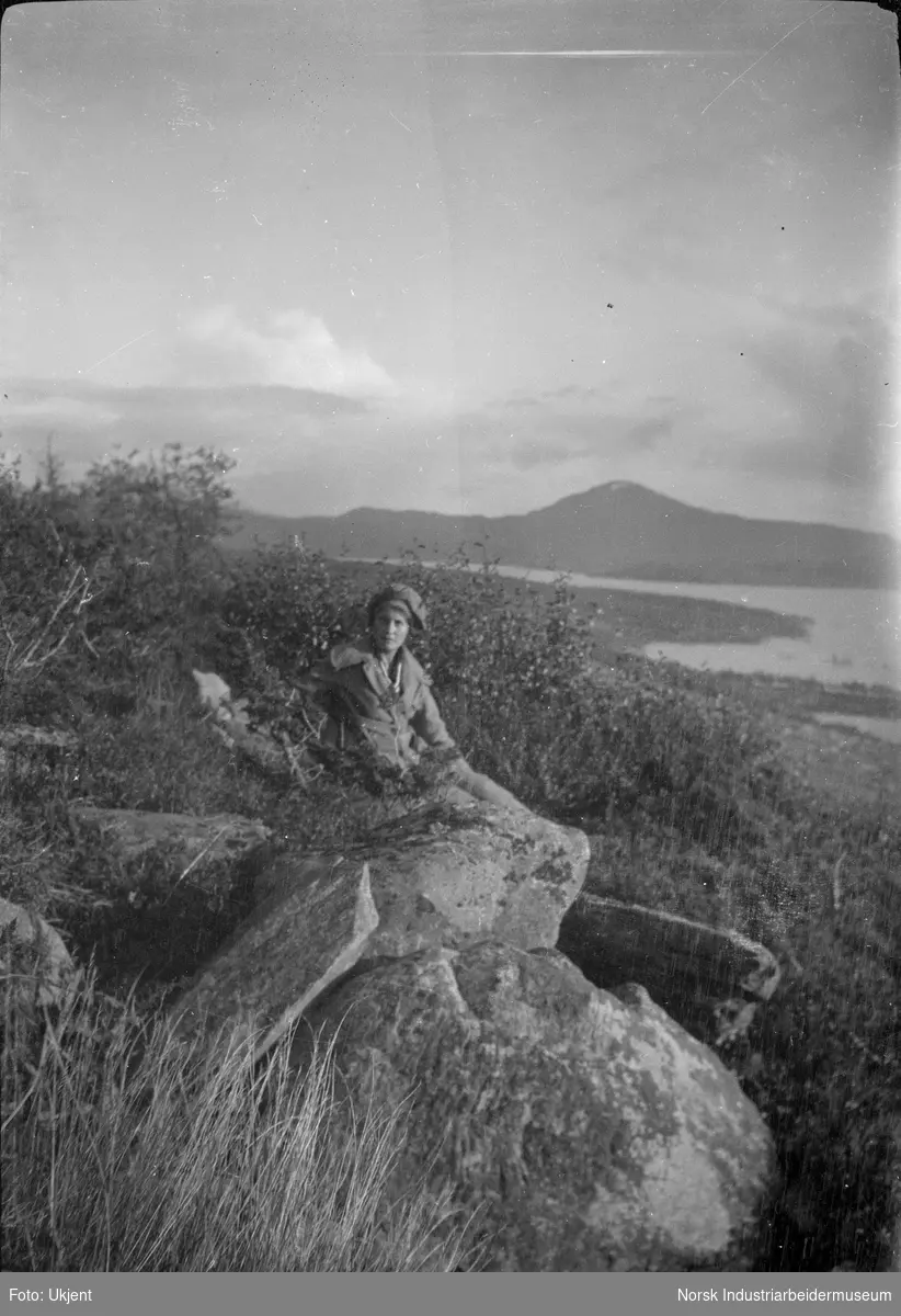 Jente sitter på en stein i naturen