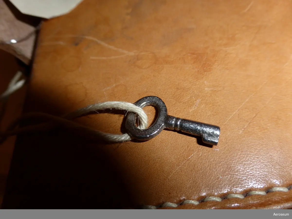 En nätskrivare i brun läderväska. Nätskrivaren har en svart sladd och är tillverkad av Staub & Co. i Schweiz. I läderväskan finns även en papperspåse med 66 stycken diagram/skalskivor. Väskans lock har ett litet lås och en tillhörande nyckel hänger från väskans bärrem.