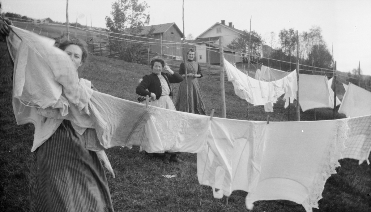 Tre kvinner henger opp klesvask, antatt på Linjordet i Østre Gausdal