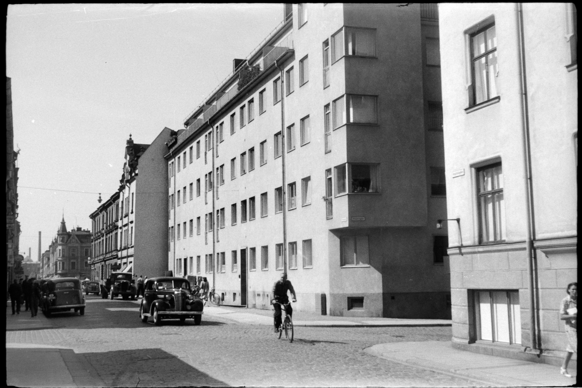 Bil och cyklist på gatstensgata i Norrköping. Cyklisten passerar över Skepparegatan, kvarteret Bakugnen. I bakgrunden syns hörnhuset i kvarteret Svärdet i korsningen med Kristinagatan.
