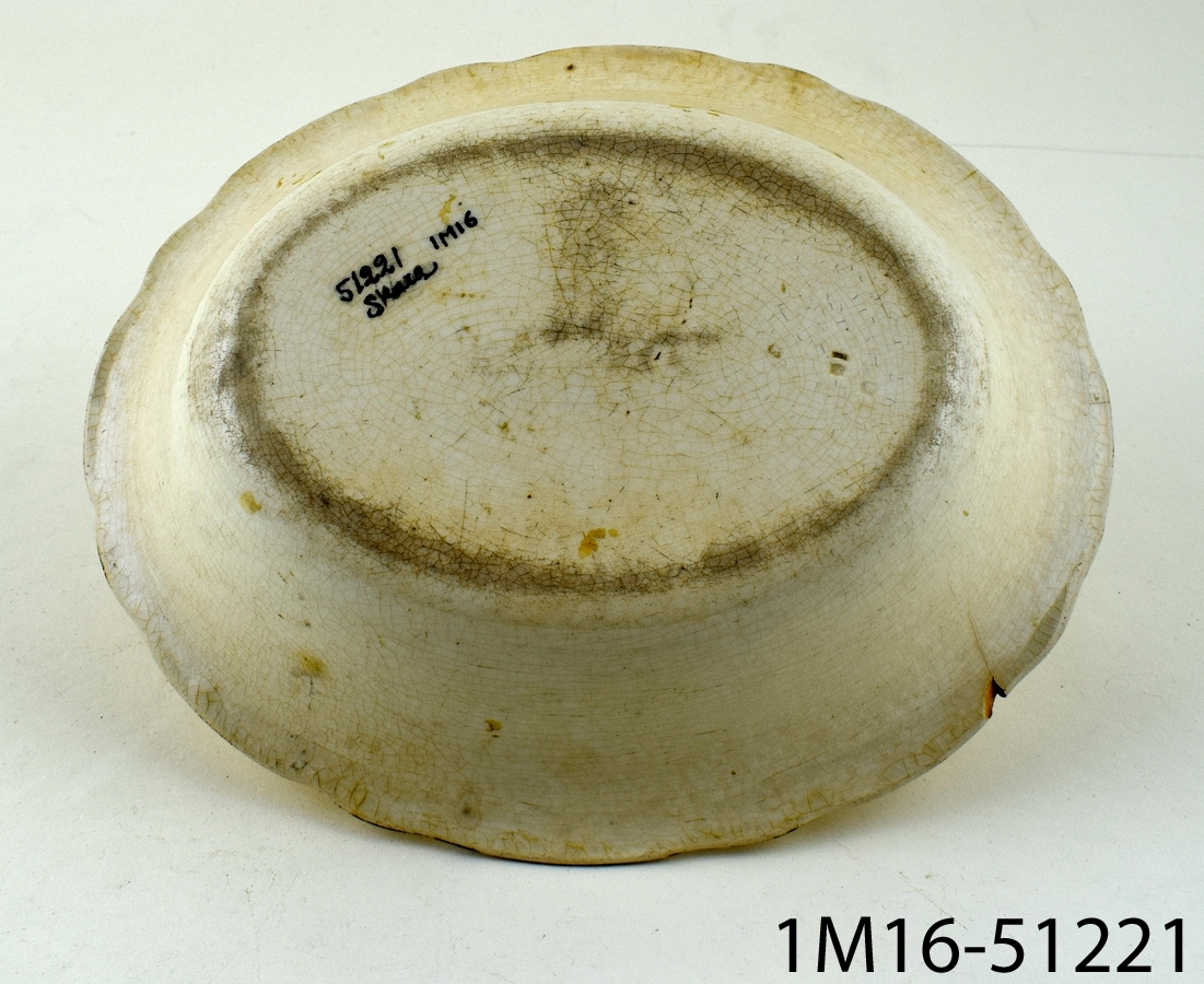 Oval karott i fajans eller flintgods med reliefdekor och vågig kant.
