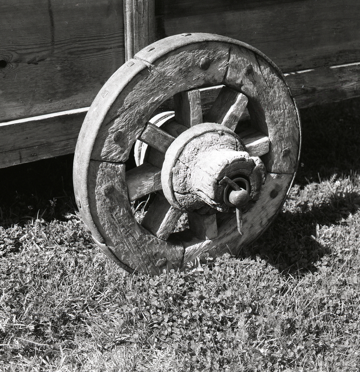 På gräset står ett föremål gjort i trä med ett trähjul på. I hästväg 27 juli 1990.