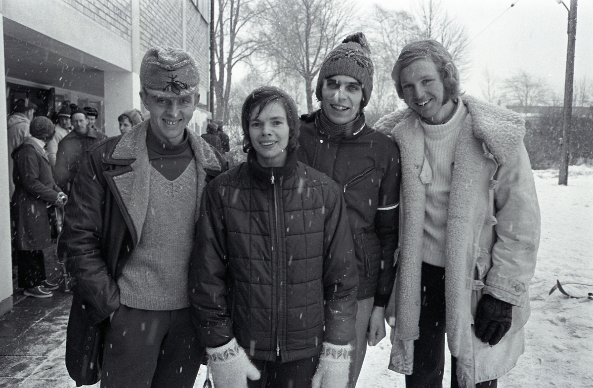 Distriktsmäterskap i skidorientering. Fyra ungdomar i ytterkläder, i snöväder. Längst till höger står Ove Thörn.
Byggnaden är Gäddgårdsskolan.