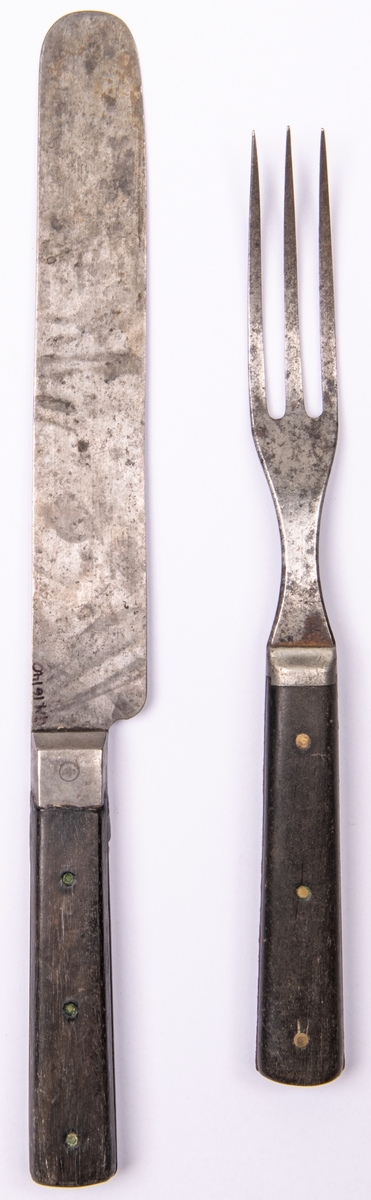 Bestick, bestående av gaffel och kniv av järn med träskaft. Gaffel har 3 klor.
