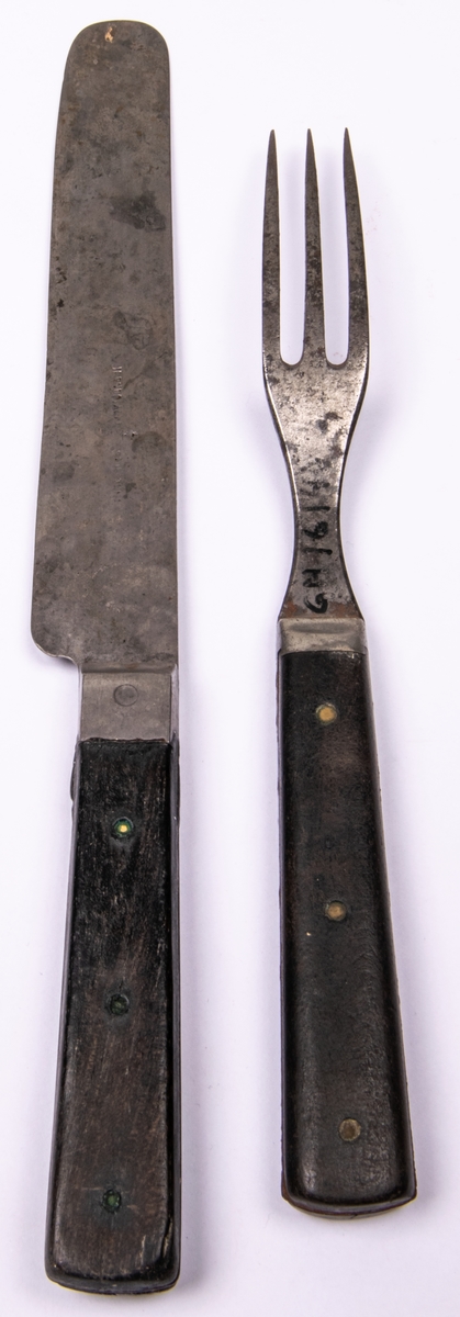 Bestick, bestående av gaffel och kniv av järn med träskaft. Gaffel har 3 klor.