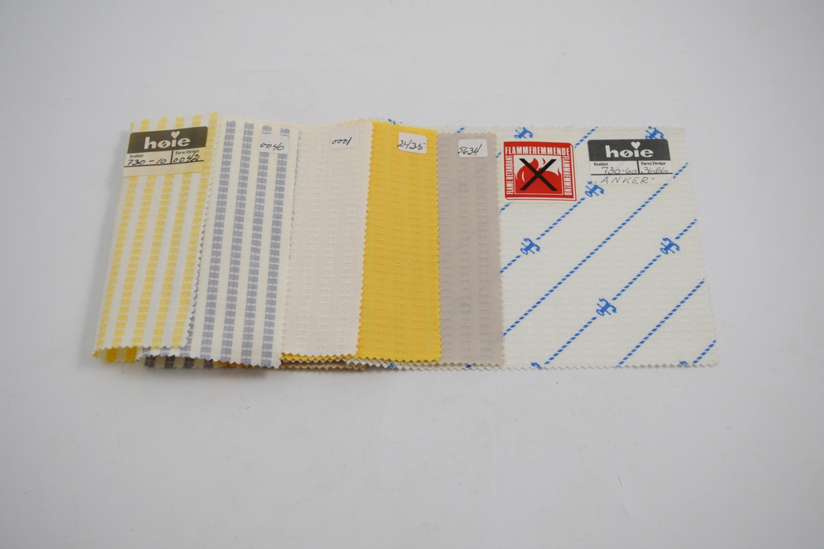 Rektangulære tekstilprøver av samme kvalitet, men ulikt design, stiftet sammen. Papirlapper er klistret til alle stoffene. Heftet inneholder kvalitet 730-10, med desingnummer: 42, 40, 1, 2435, 5634, 3656 ("Anker").