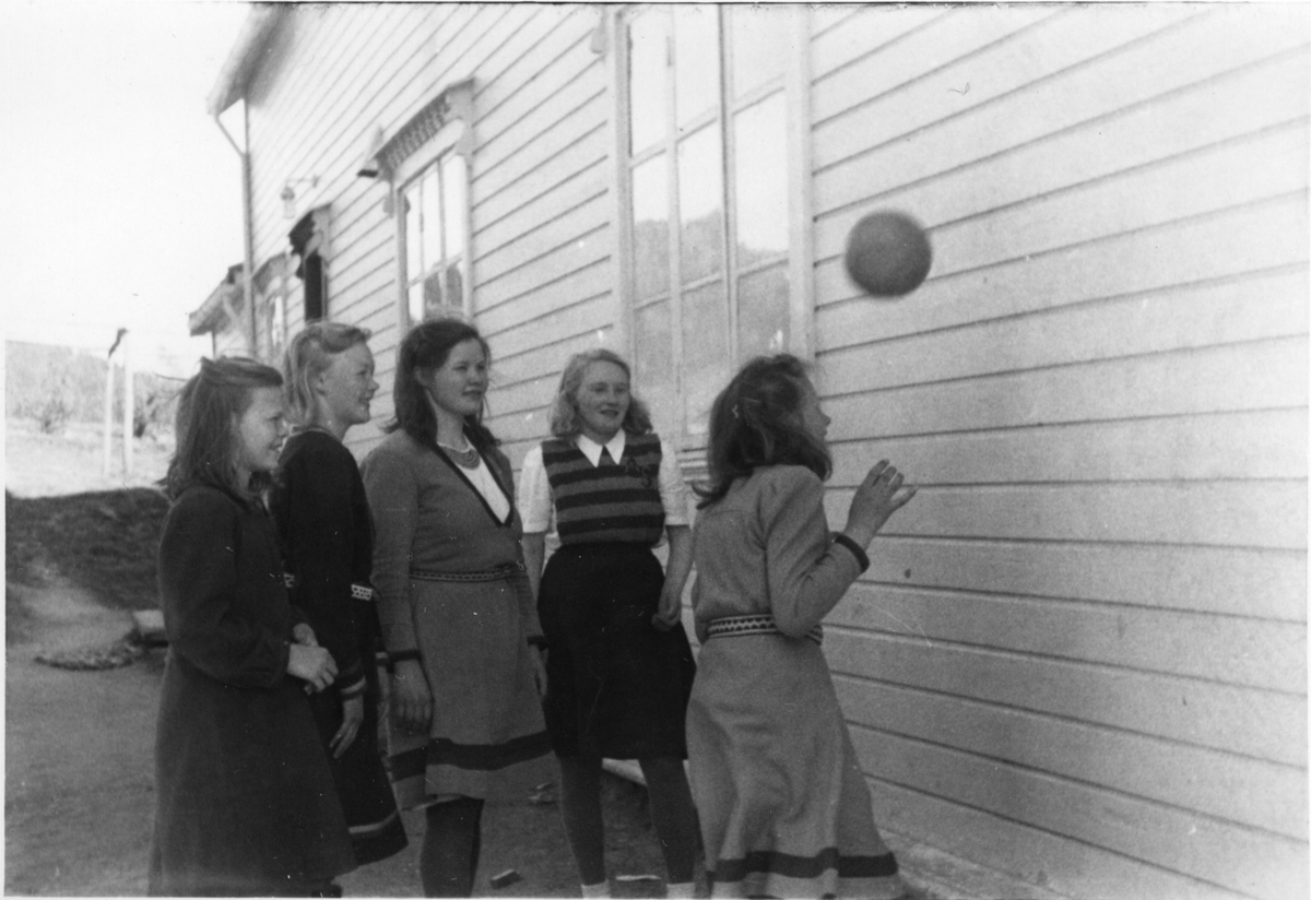 Fem unge jenter i ballek ute på gården foran sameskolen i Havika