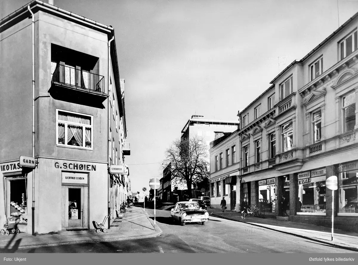 Torggata i Sarpsborg, 1950-60-åra. Til venstre hjørnegården til Gjertrud Schøien (garn og trikotasjeforretning) i Karl Johans gate 10.