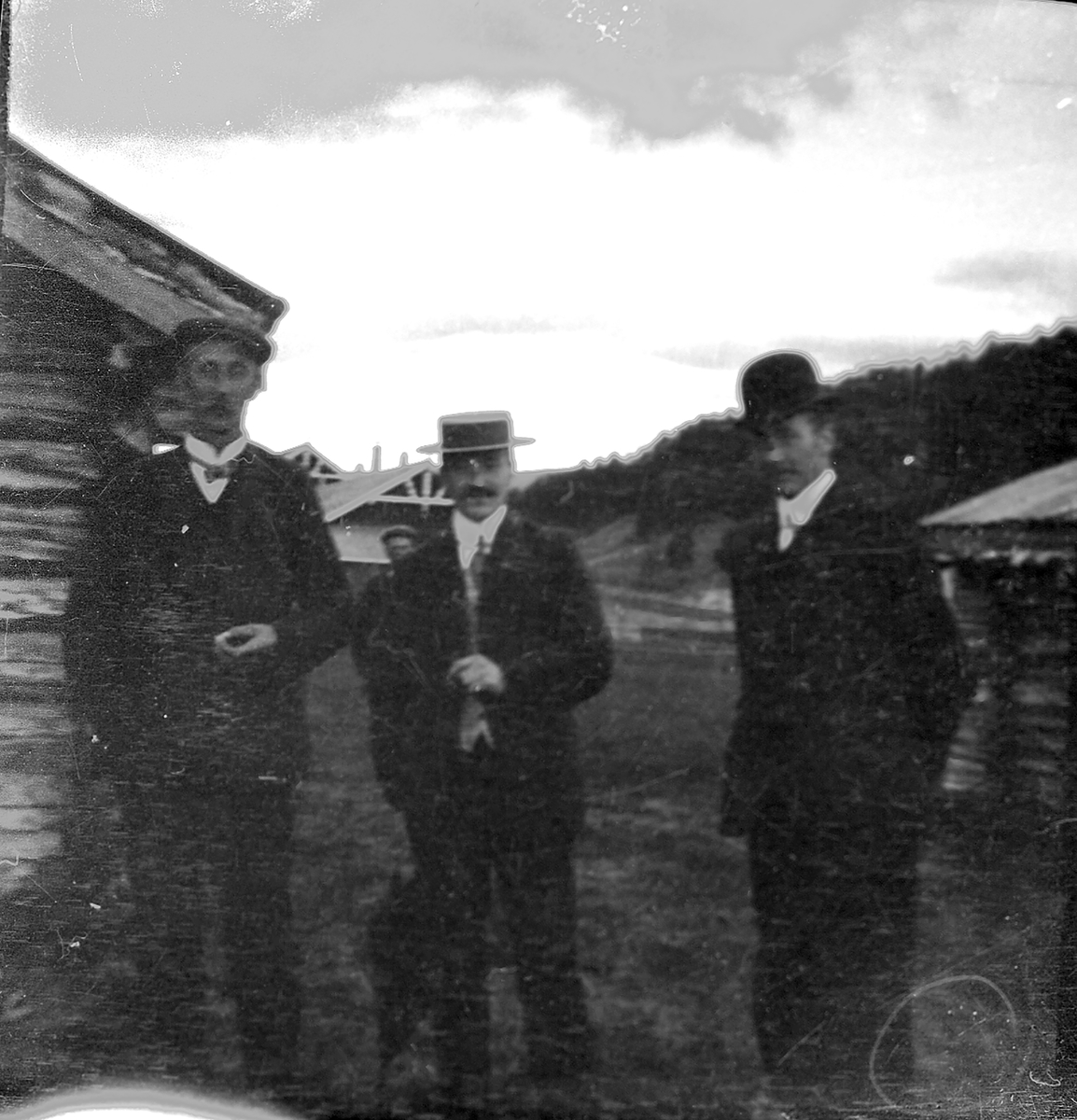 Tre menn ved hytte