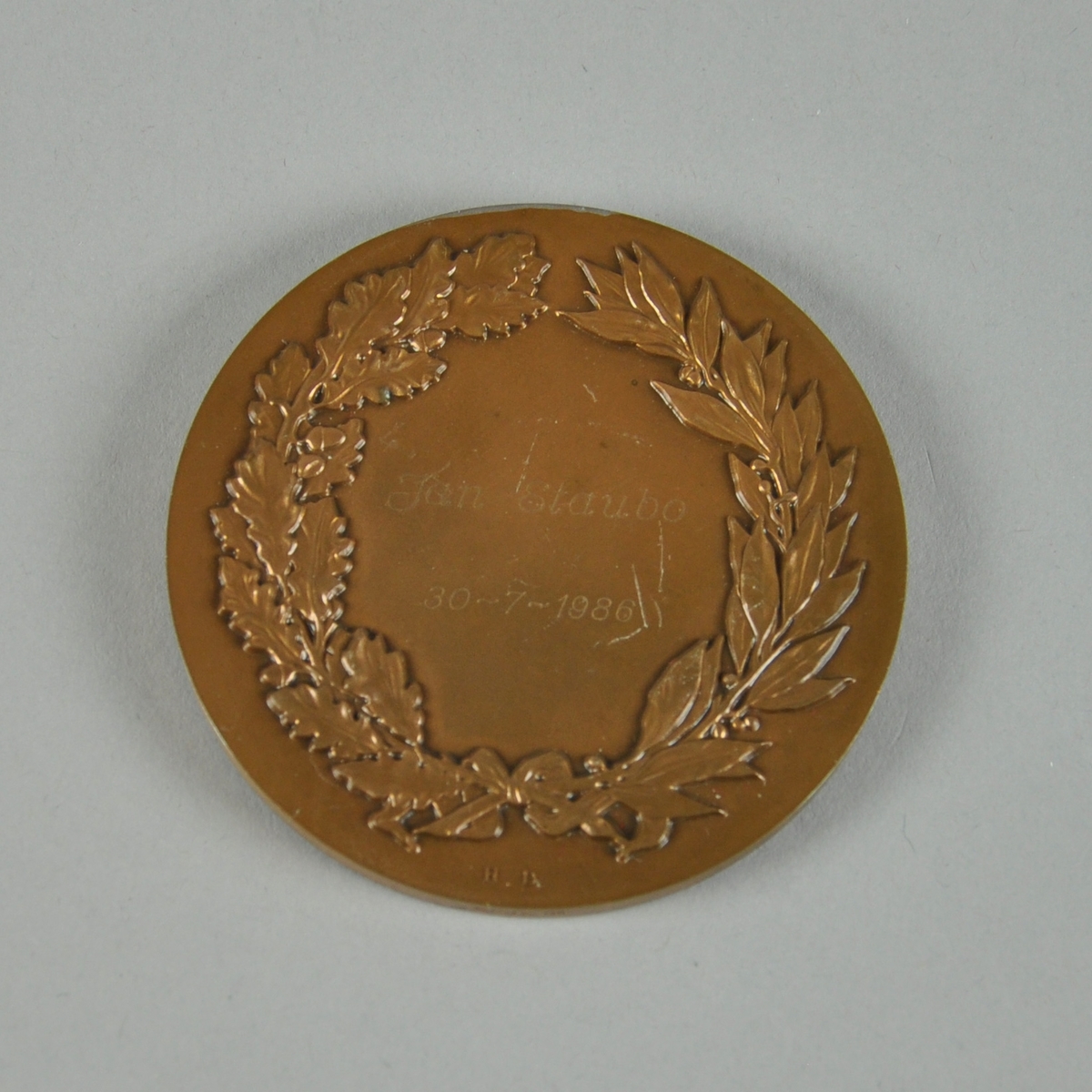 Bronsefarget medalje med motiv av to våpenskjold og det som ser ut til å være en olivenkrans. Med medaljen følger det en boks. Ligger i en rød eske av kartong med rødt fløyelsfôr og hvitt silkefôr.
