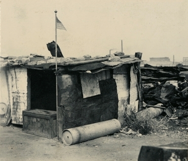 Boligbrakke i "Ørken Sur", Brooklyn NY, ca 1929-1935. Amerikansk flagg heiset på bambusstang ved døren.