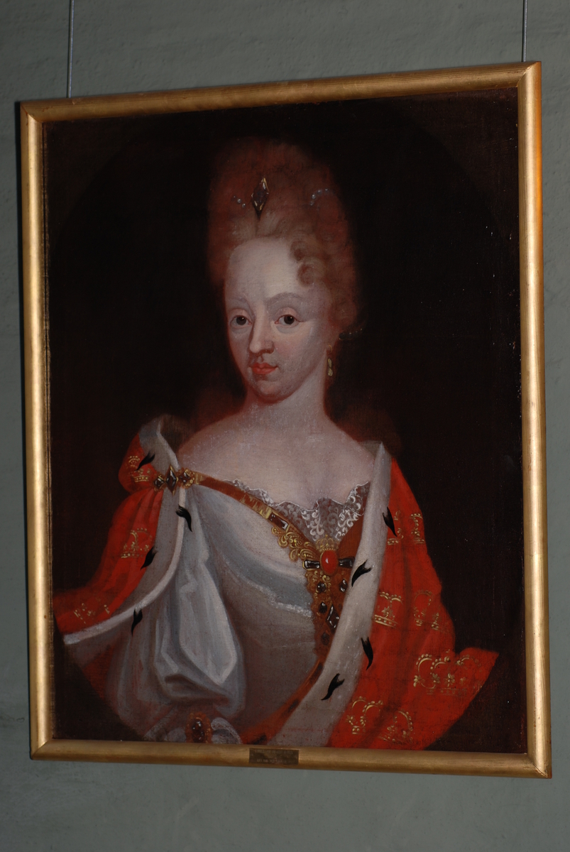 Olje på lerret, portrett av Louise av Mecklenburg (død 1721, gift med Fredrik IV). Halvfigur. kroppen i kvart profil mot høyre, hodet i kvart profil mot venstre. Hvit kjole, over skuldrene en rød kappe med gullkroner og hermelinskanter. Forgylt ramme. 