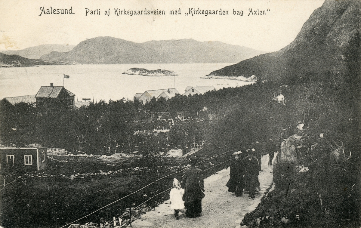 Oversiktsbilde av Kirkegårdsveien og Kirkegården på nordsiden av Aksla i Ålesund. På veien går det flere mennesker i pene klær(gravfølge?).