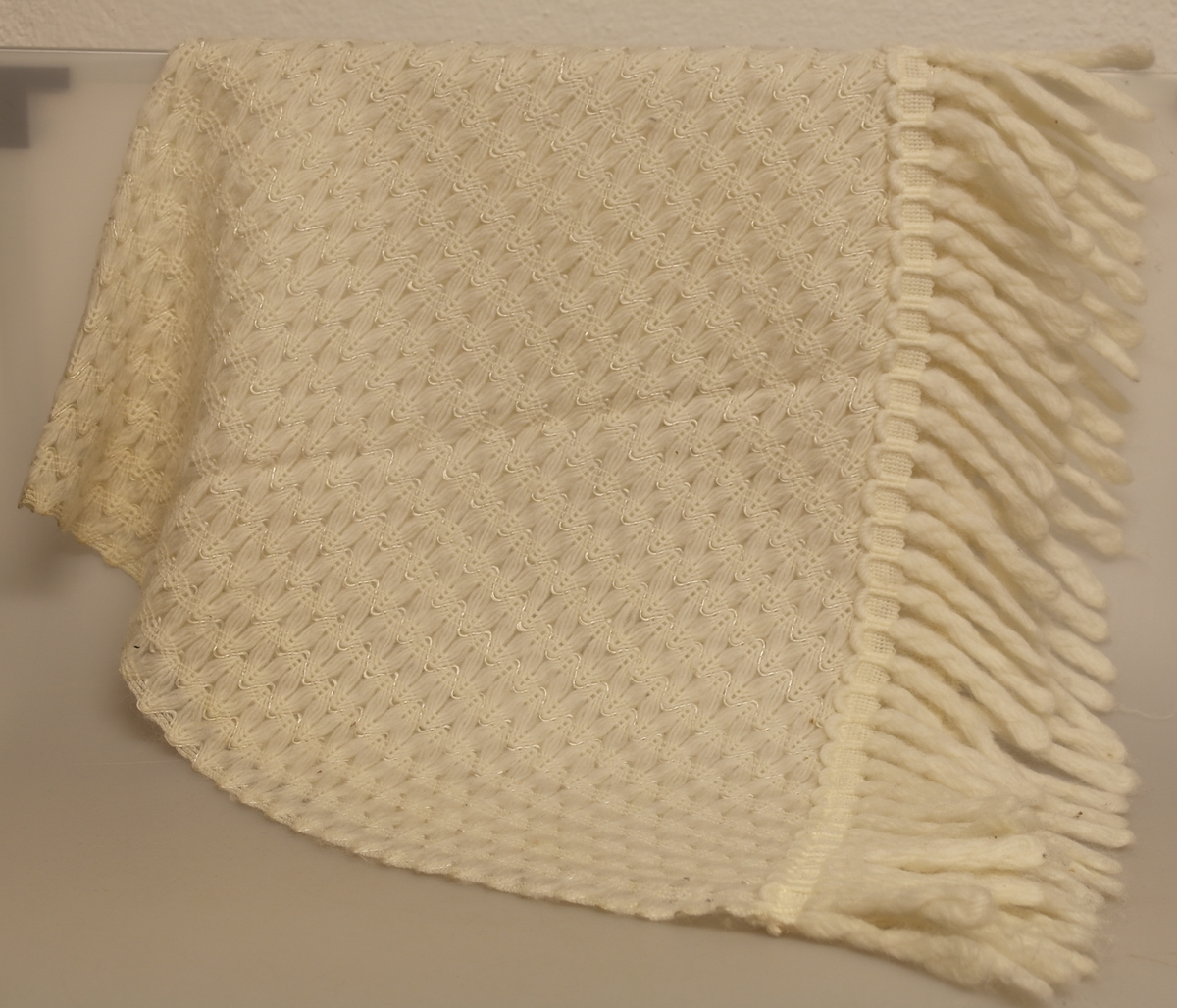 Offwhite sjal med frynser. Sjalet har ifelt silkeliknende tråd som del av mønsteret.