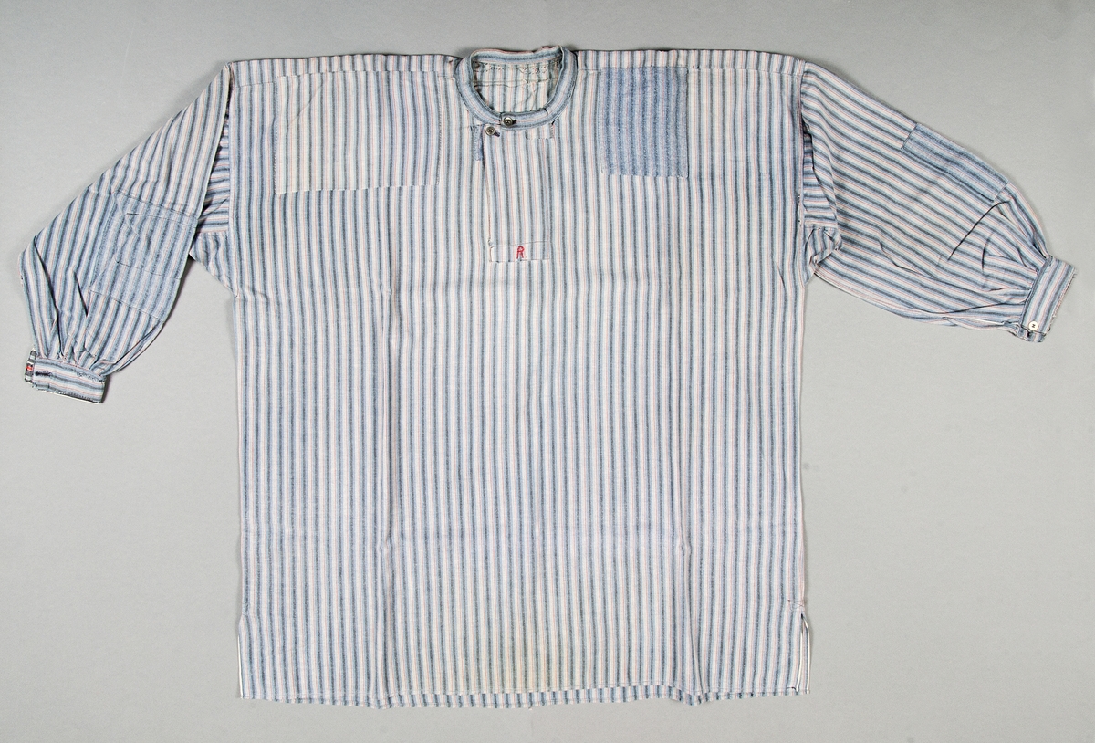 Skjorta av bomullsflanell med vävda ränder i blått, svart och rött. Skuren i en fram- och en bakvåd med besparing. Smal halslinning knäppt med två metallknappar och knapphål. Halssprund med förslag med initialen "R" (= Rikard Eugén) utförd med rött bomullsgarn i klyvsöm. Rakt isydd ärm med ärmspjäll, rynkad mot manschett, 4 cm bred, och knäppt med vit pappknapp och knapphål. Förstärkta sprund i sidsömmarna nedtill. Lappad vid axlar och på ärmar. Halslinningen antagligen utbytt mot ny. Manschetten förstärkt på insidan med nytt randigt tyg. 