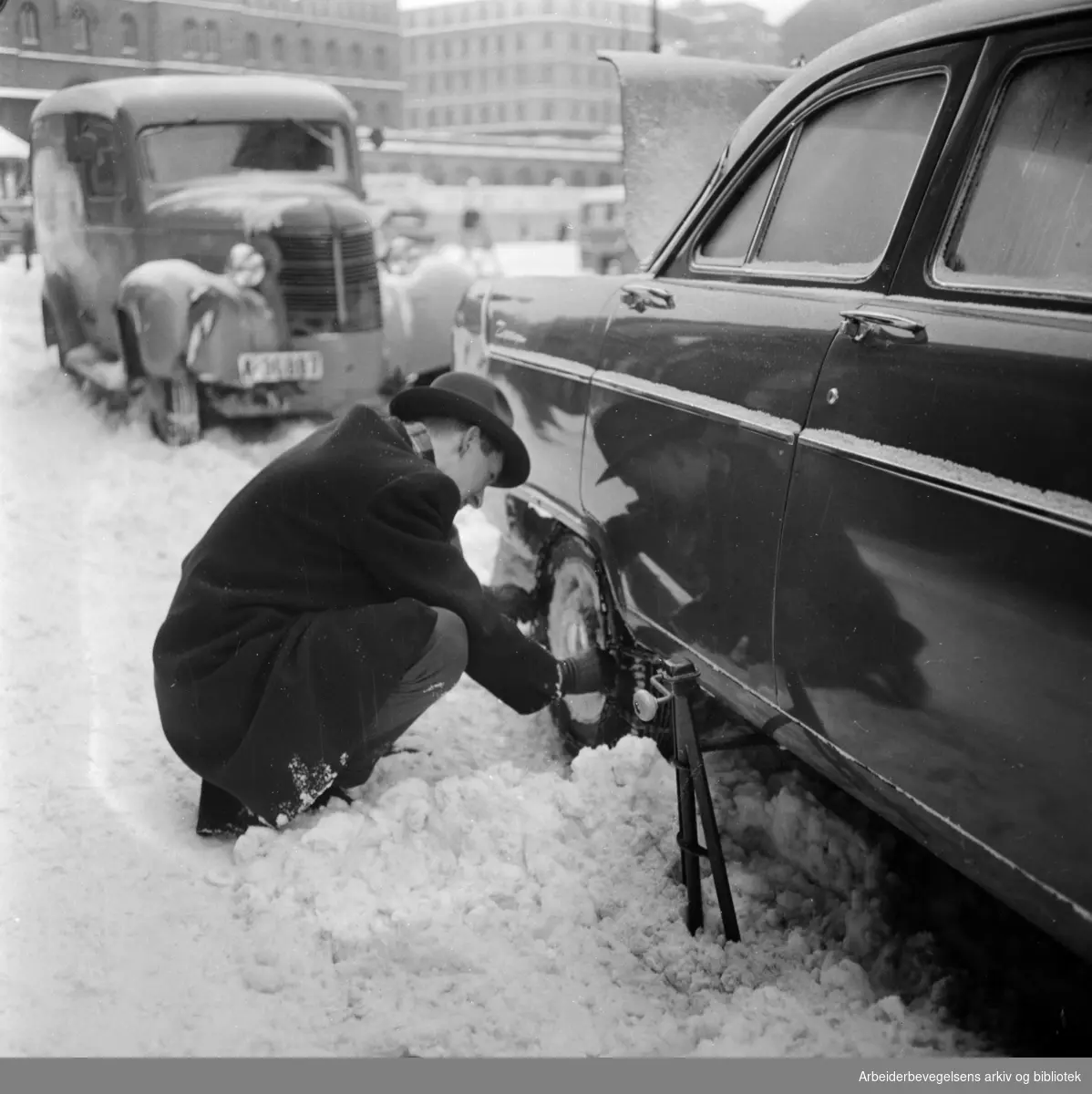 Uventet kraftig snøfall i Oslos gater. Montering av kjettinger. 1. Mars 1960.