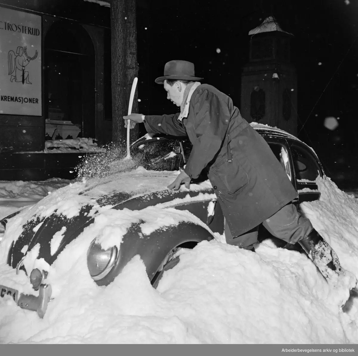 Mann graver fram nedsnødd bil. Akersgata. Desember 1959.