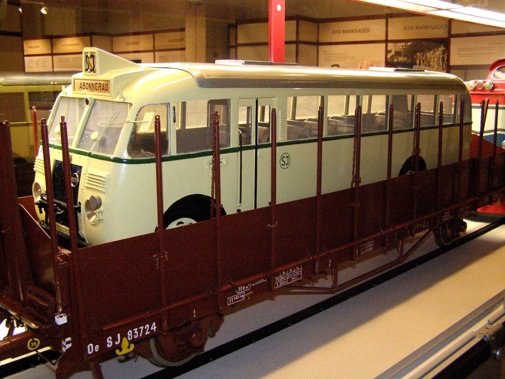 Modell av buss i skala 1:10. Bussen är gulmålad med grön rand, och SJ:s logga inom ring i grön färg. Grått tak. Detaljer i svart. Byggd för vänstertrafik
Upplastad på vagn (Jvmf 12895).