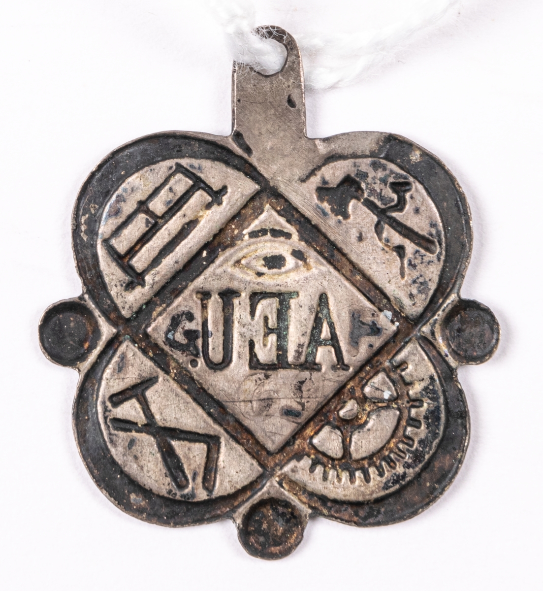 Föreningestecken i pressat silver, för okänt sällskap. Med emblem för olika hantverk, så som yxa, såg, hammare, vinkelhake och kugghjul, samt AEU.